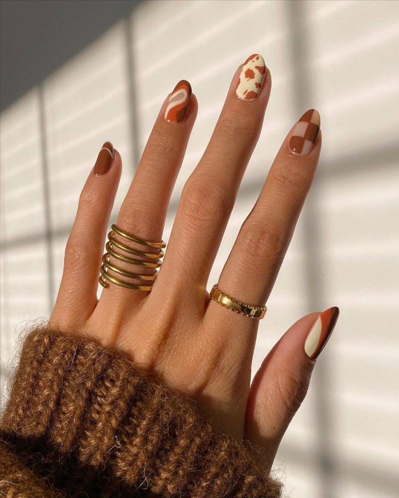 Autum tones for Nail Art, womans hand with browns and creams in different patterns painted on her nails