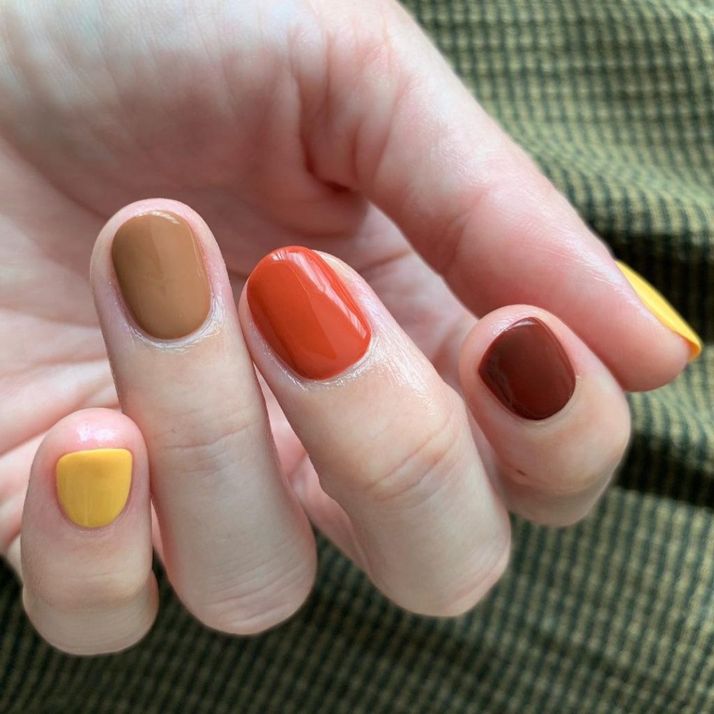 short nails with nail art in yellow, coffe, organge and brown