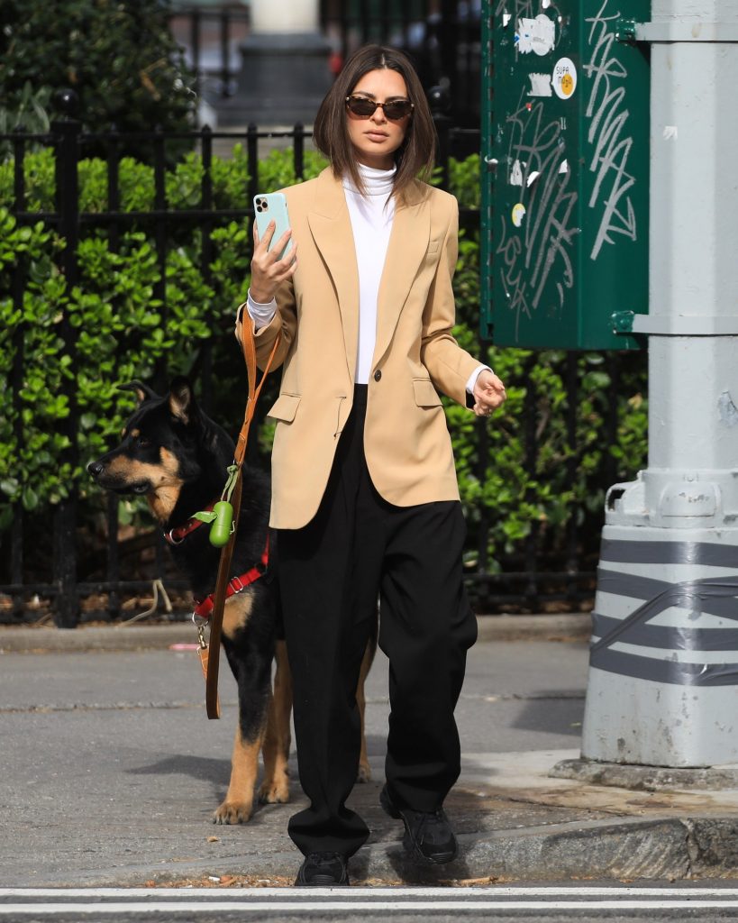 Woman in beige blazer walking an Alsatian dog