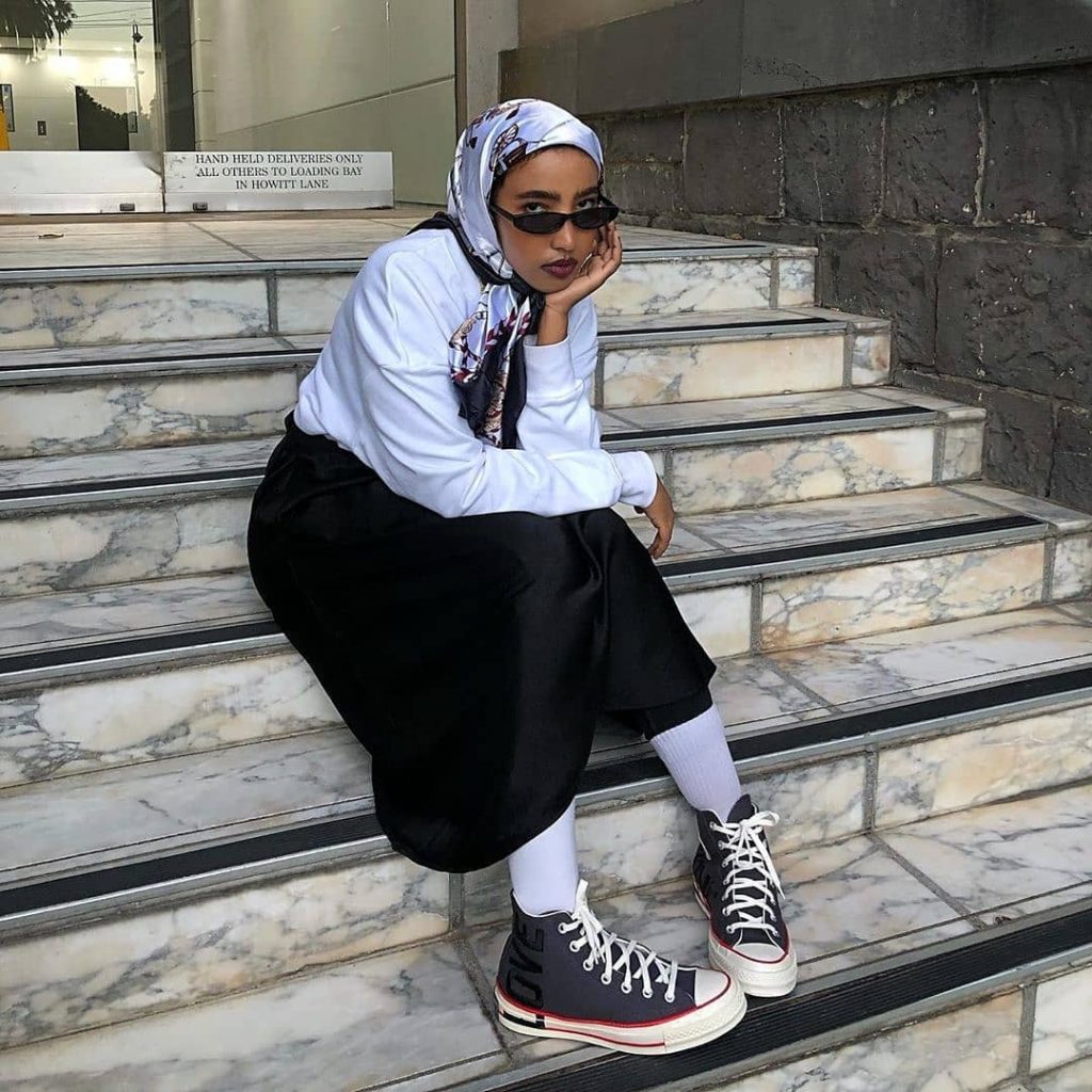 Converse - one of 10 best sneakers worn by seated woman with headscarf and black culottes