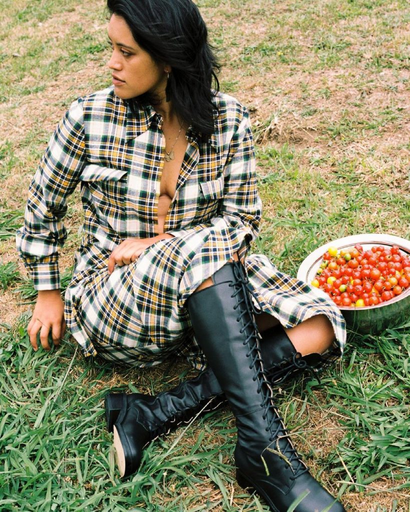 Woman sittin on grass in check dress and black knee high boots