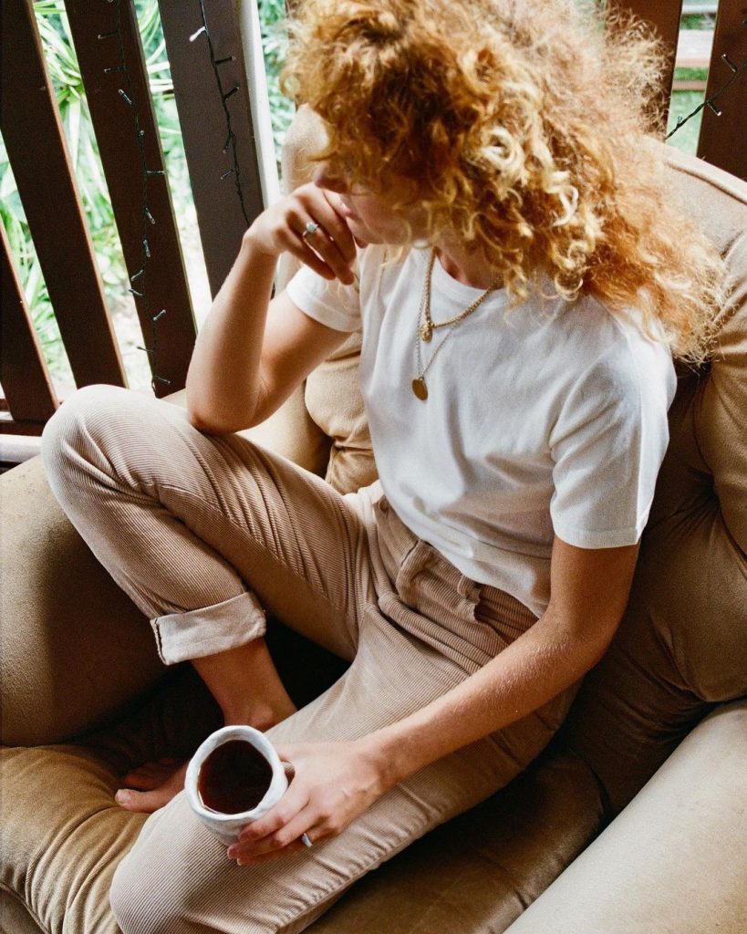 woman wearing sustainable fabrics holding a cup of coffee